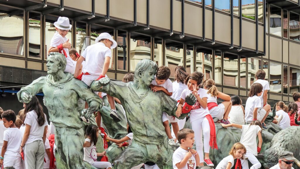Monument to the Encierro, with children hanging on it during the day, posing for pictures.