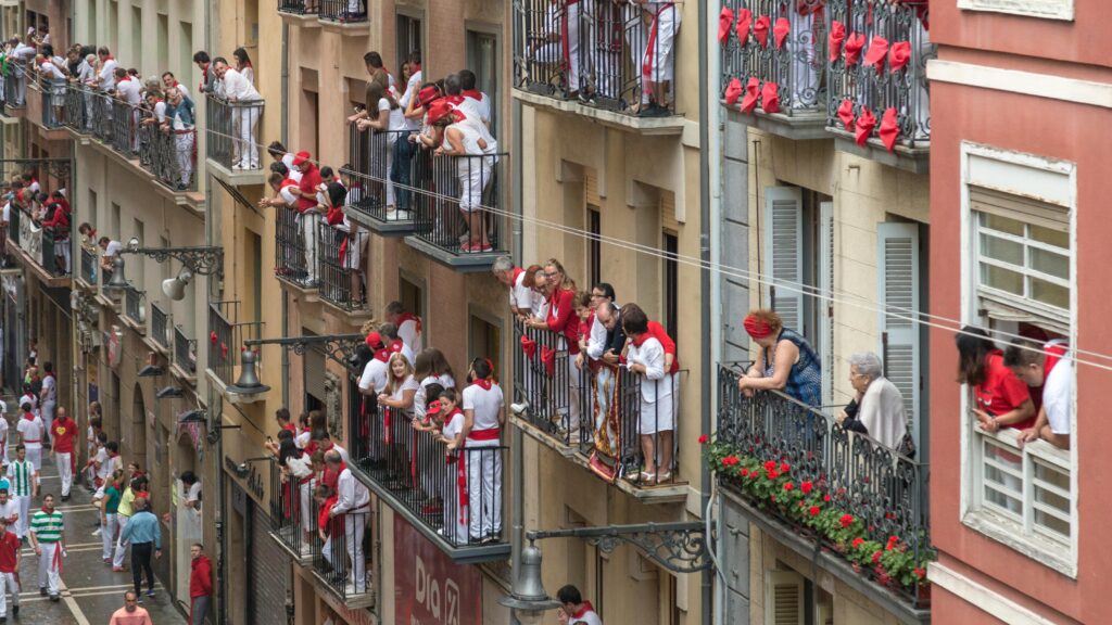 Revelers on balconies along Calle Estafeta, looking down, waiting for the bull run (encierro).