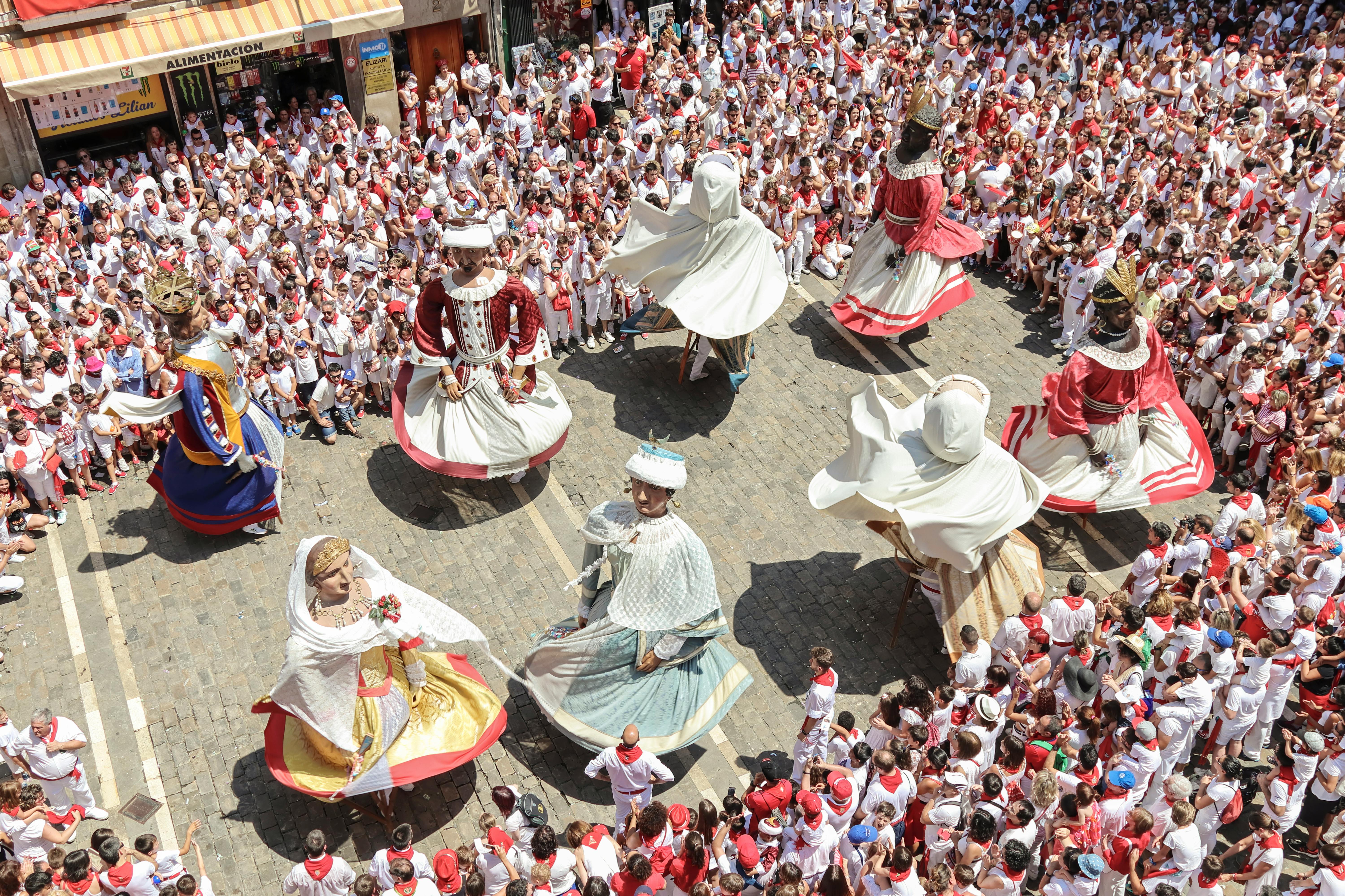 Los Gigantes (the Giants) dancing during a daytime procession in the Plaza del Ayuntamiento, surrounded by revelers during San Ferm&iacute;n