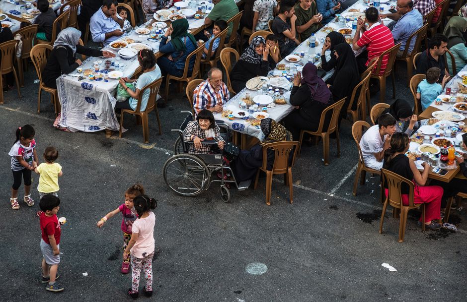 Outdoor communal table with people sharing a meal in the street during San Fermin Pamplona