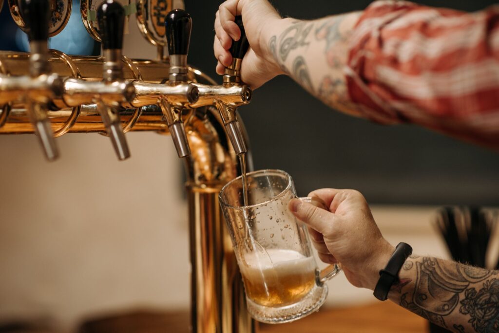 Bartender pouring a cold draft caña at a bar counter in Pamplona during San Fermines