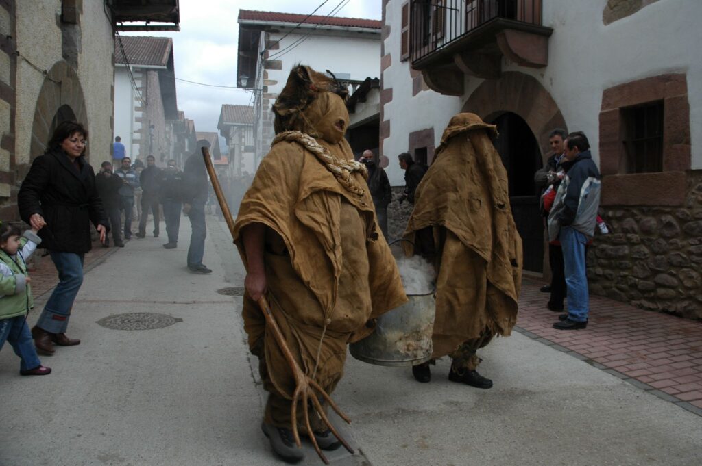 Masked zarrapalderos with a smoking cauldron at the Carnaval de Lantz procession, Navarra
