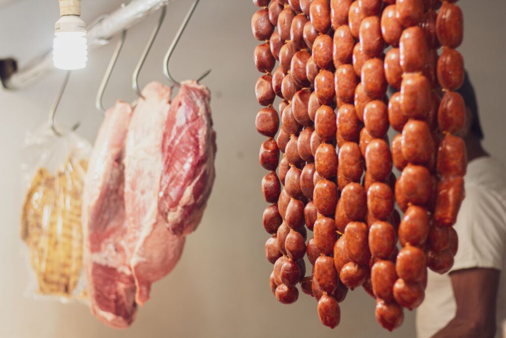 Strings of red chorizo hanging to cure on hooks in a butcher shop