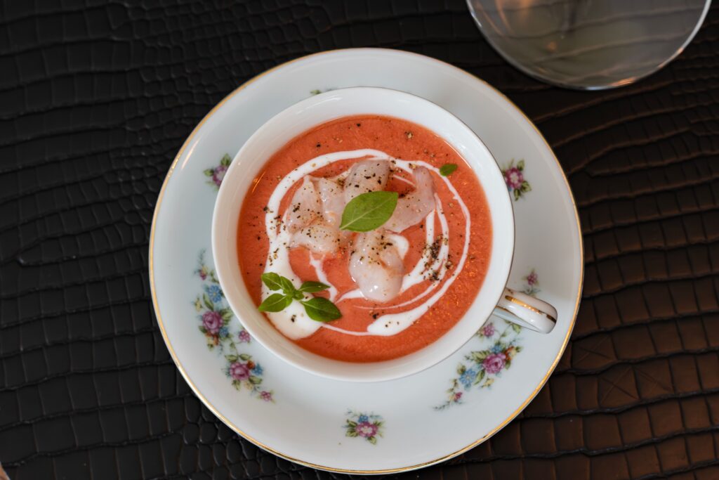 Chilled gazpacho tomato soup garnished with basil, a Spanish summer staple