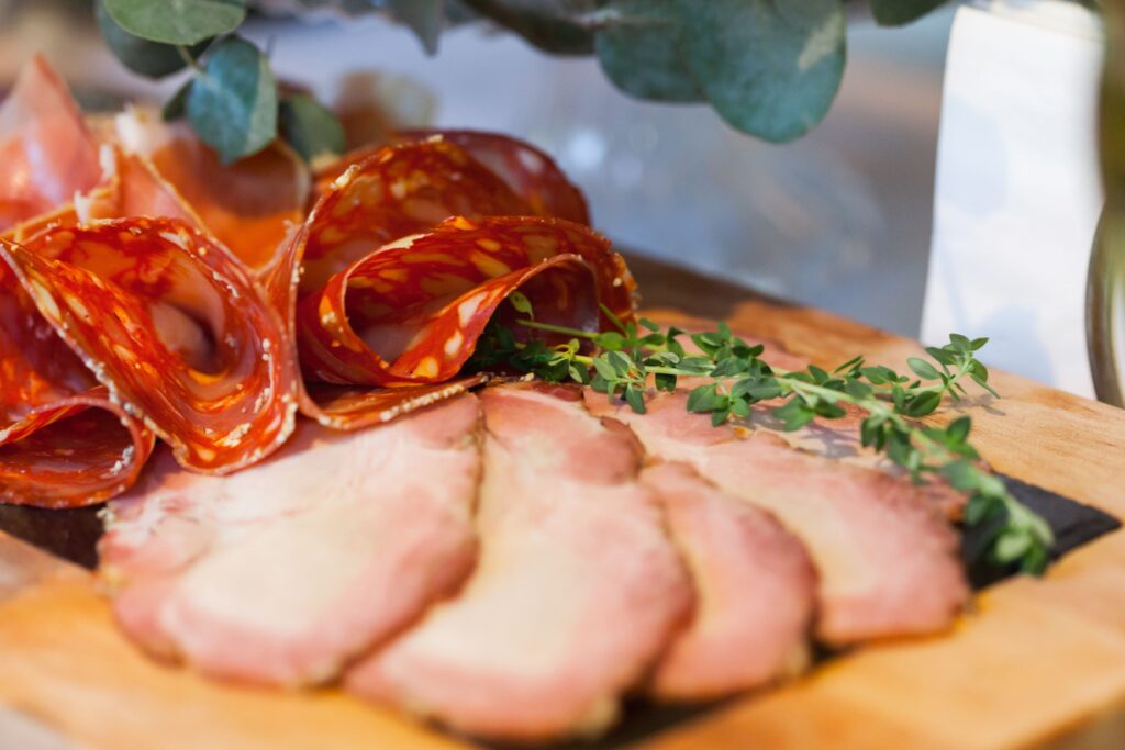 Thinly sliced lomo embuchado cured pork loin on a wooden board, Spanish bar tapa