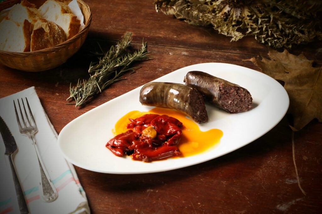 Sliced morcilla blood sausage with roasted red peppers on a rustic plate