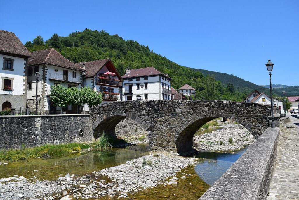 Medieval stone bridge over the Anduña river with whitewashed houses, Ochagavía, Navarrese Pyrenees