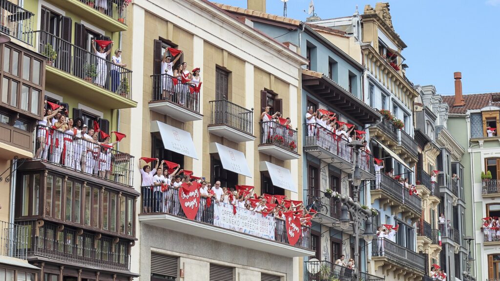 Fiesta crowd in white with red panuelos on Pamplona balconies during San Fermin