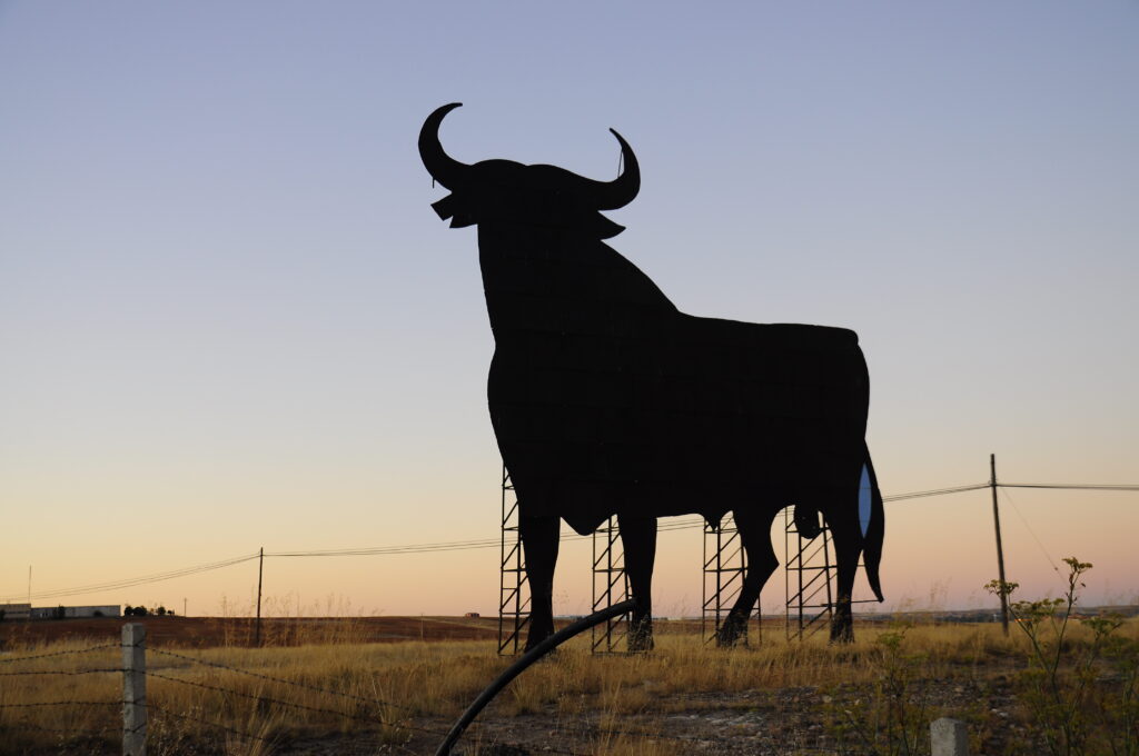 Black Toro de Osborne bull silhouette billboard on a hillside beside a Spanish road