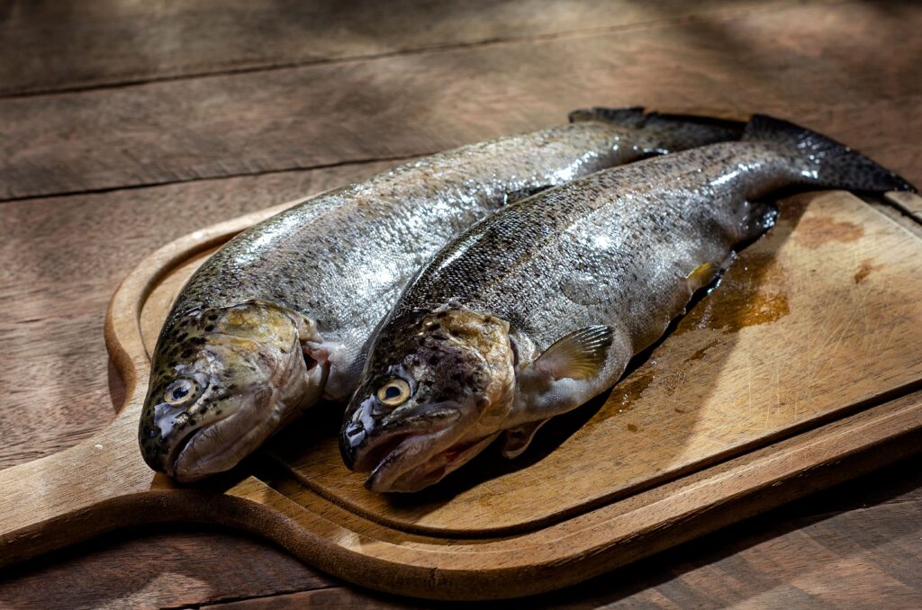 Whole raw trout on a wooden board, used to make truchas a la Navarra